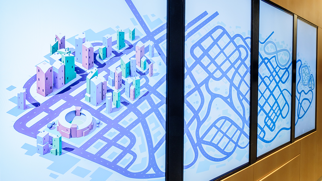 Medium full shot of the Road to Zero foyer activation, four vertical screens displaying a stylised cityscape.
