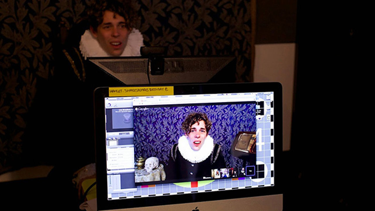Shakespeare actor on a webcam, video footage played through a laptop in the foreground.