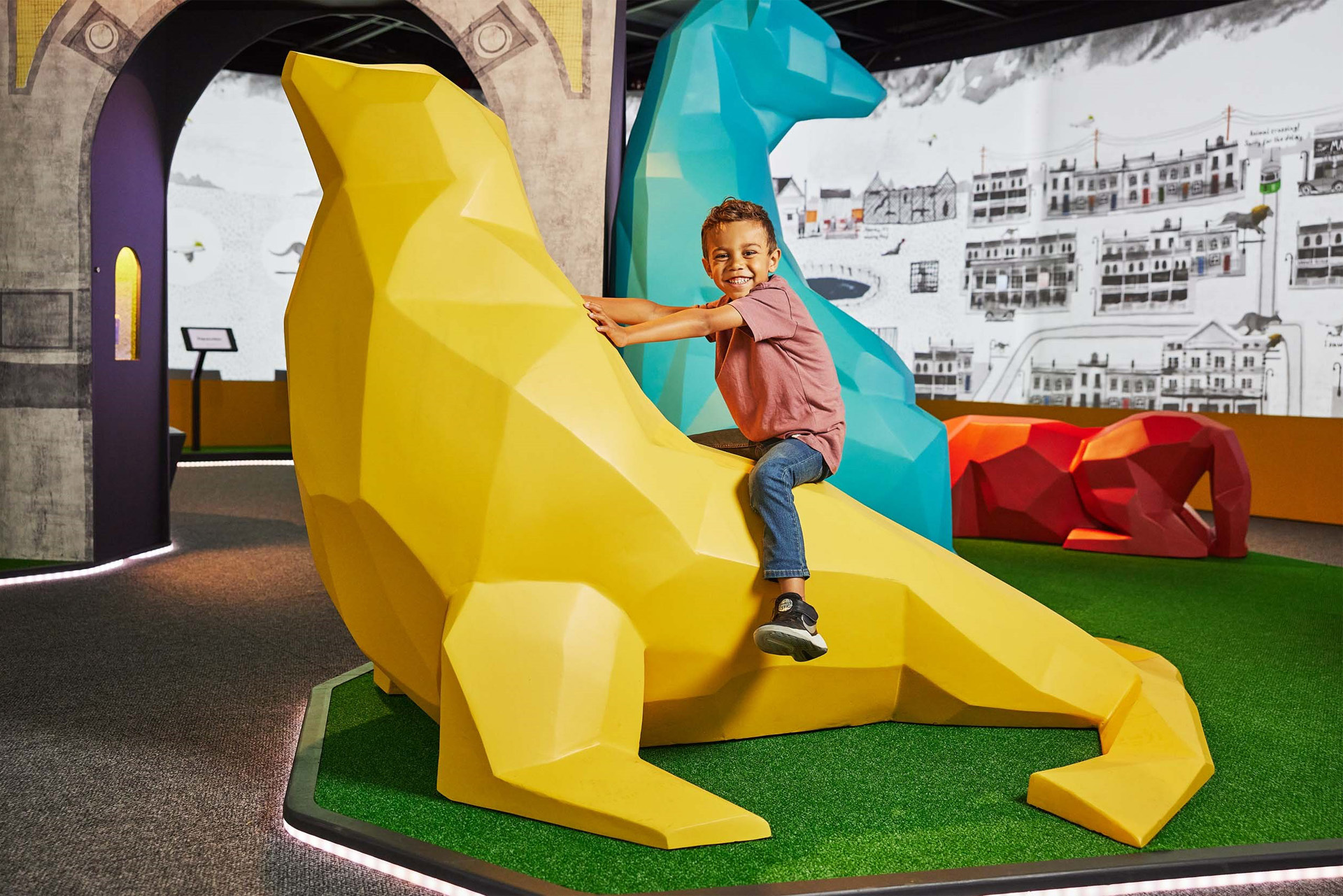 Boy riding large yellow model of a seal