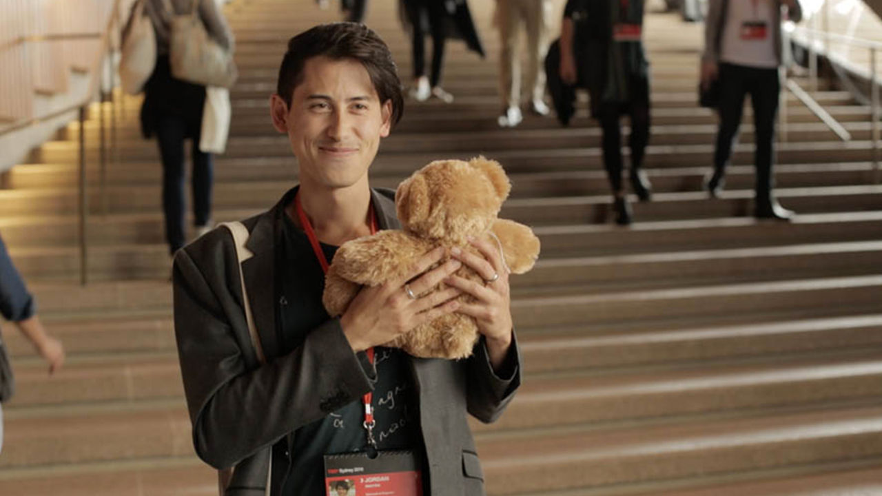 Man holding a TeddyX bear in the Opera House.