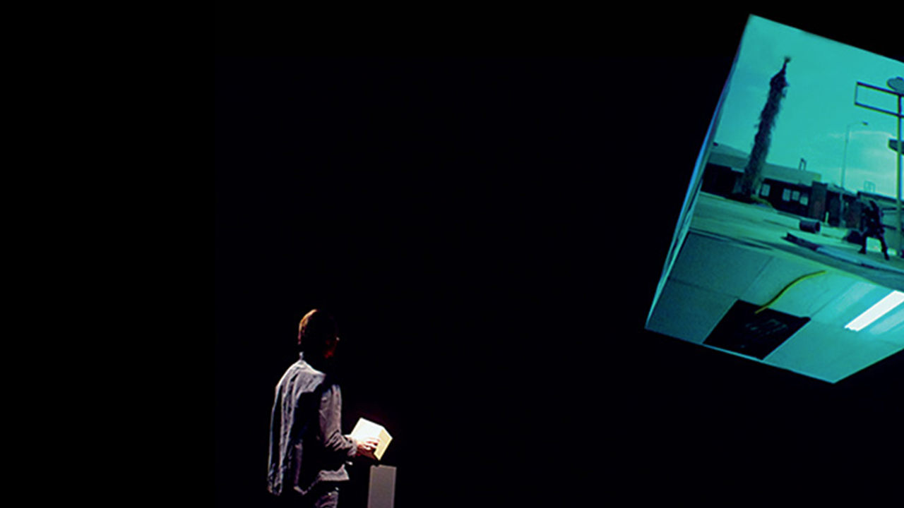 Man holding The Cube, interacting with video played on a larger 3D projected cube.